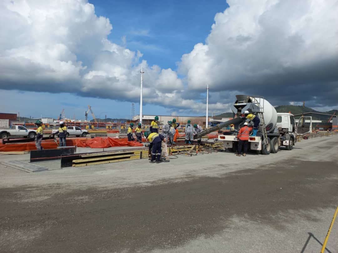 Construction crew pouring concrete for a spoon drain at Motukea Port.