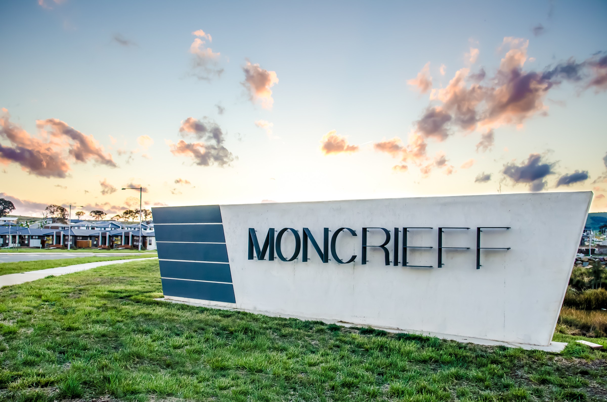 Moncrieff entry sign set into grass beside paths and the residential neighbourhood.