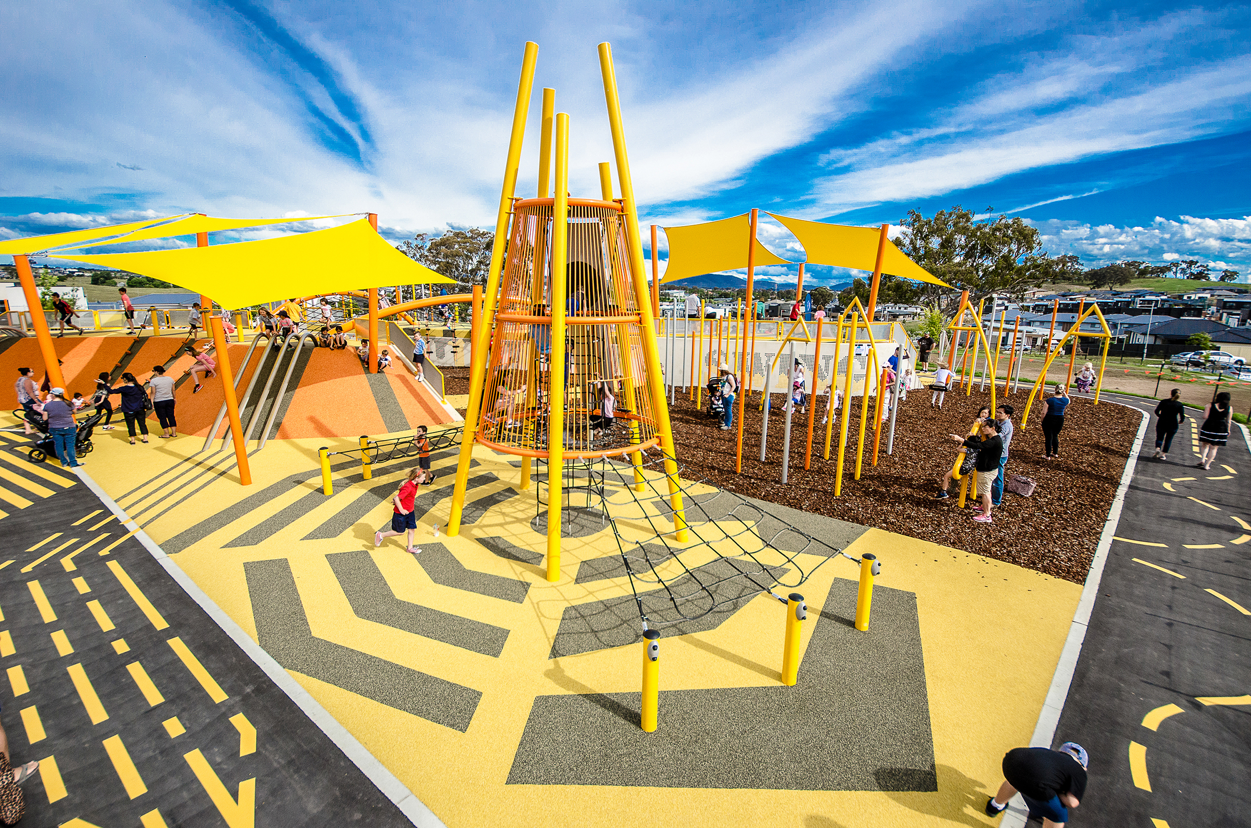 Yellow climbing structures and patterned play surfaces at Moncrieff Community Recreation Park.