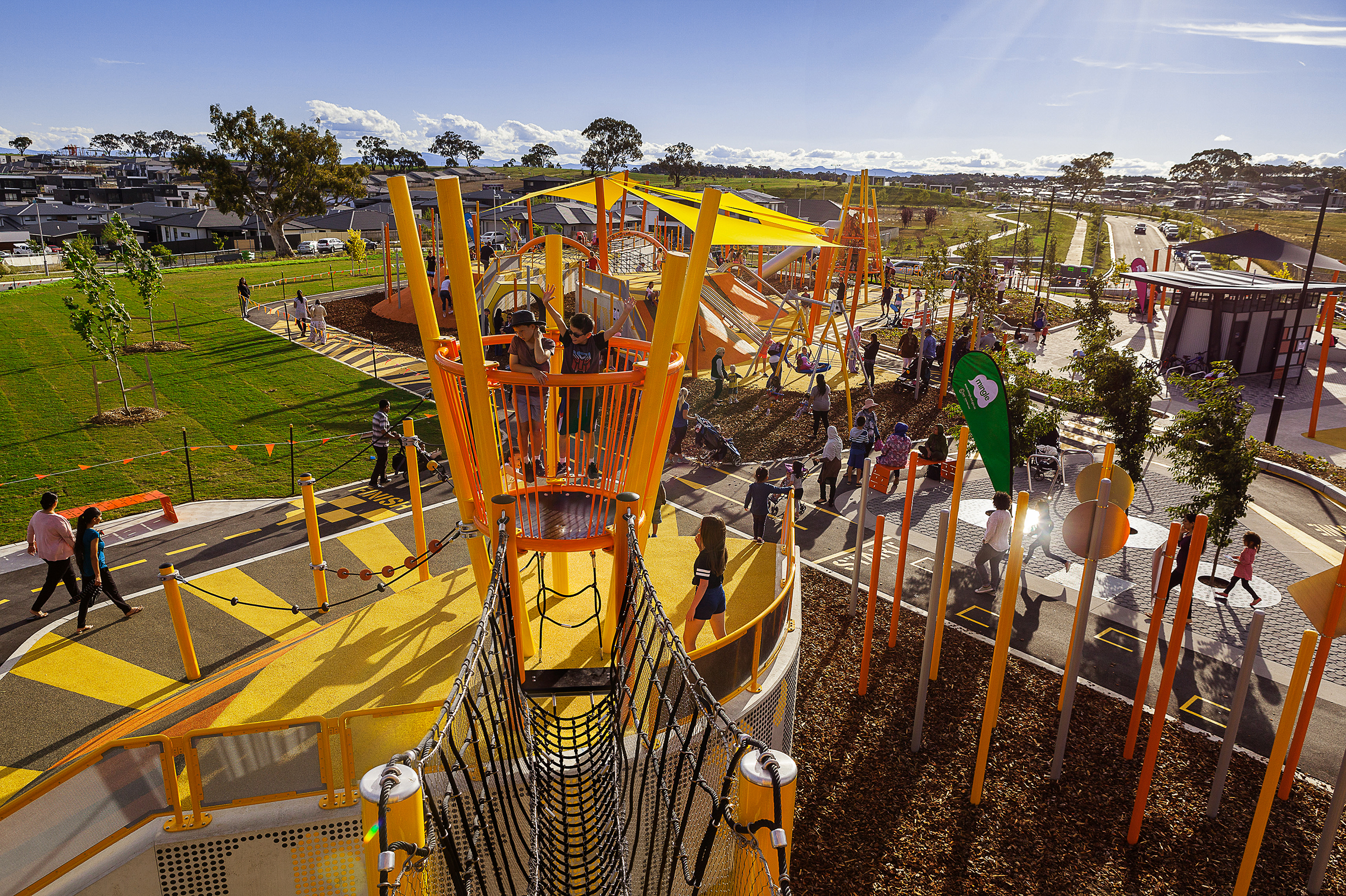 Play structures, paths and shade sails across the terraced recreation park.